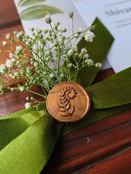 A macro shot of the custom wax seal on the S&A engagement invitation. The intricate design, combined with the texture of the velvet ribbon and the delicacy of the baby's breath, highlights our attention to the smallest details.