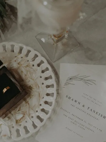 A flat-lay style shot of the engagement invitation next to the ring box.