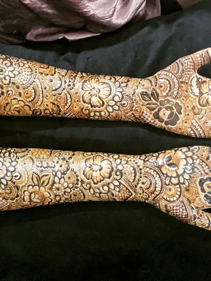 A stunning, high-contrast design with bold floral work that covers the arms from fingertips to elbow.