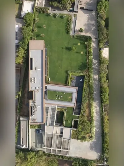 An aerial view of the "Copper House" property, showing how the extensive lawns, perimeter trees, and rooftop gardens are woven into the architectural layout. The landscape becomes an integral part of the building's identity.