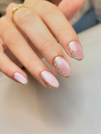 Simple, minimal, and so glittery. This elegant look features a soft pink cat-eye base with a delicate border of gold glitter around the cuticle.