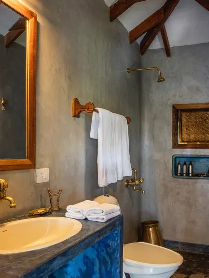 A bathroom in the Sky Room at Jalakara, featuring a rich blue polished cement vanity and brass fittings.