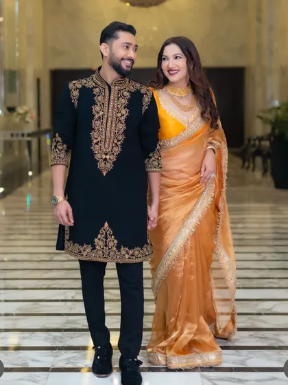 The complete look. Our black sherwani with detailed gold threadwork on the collar, placket, and cuffs, paired with tailored trousers for a sharp, regal silhouette.