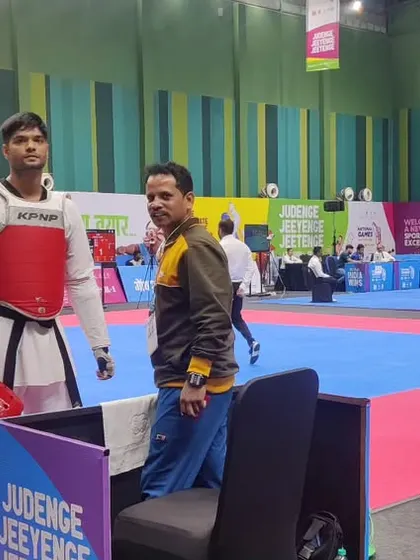 A moment of focus before the match begins. I stand by our athlete's side at the National Games, ensuring he is mentally and physically prepared for the fight.