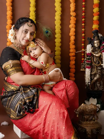 A tender embrace between a mother and her baby, dressed as Radha and Krishna.