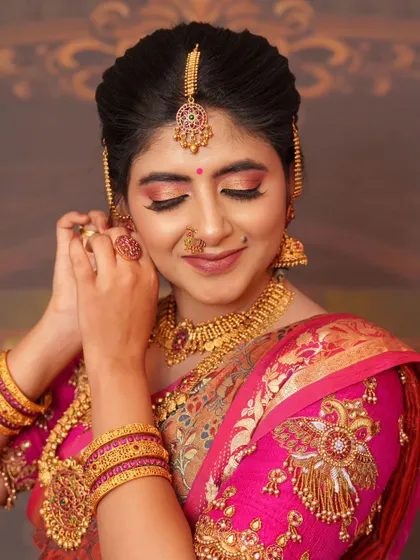 Getting ready for a show, putting on the final touches. This look, with heavy gold jewelry, is fit for a grand wedding celebration.