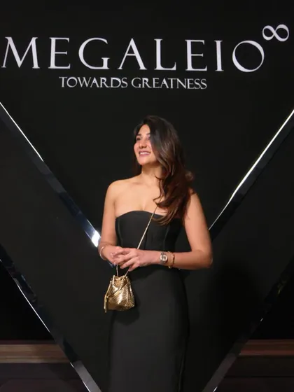 A close-up of the event look. The minimal black dress allows the accessories, like this small gold bag, to stand out.