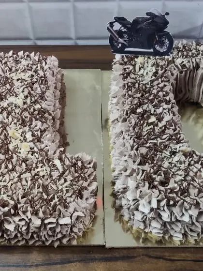 A number cake for a 20th birthday. This chocolate cake is shaped into the numbers '2' and '0' and topped with a motorcycle accent.