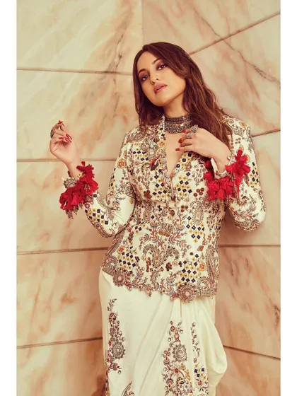 A close-up of the Anamika Khanna outfit, showing the intricate mirror work and the playful red tassels on the sleeves.