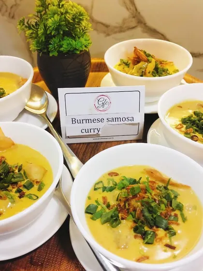 Samosa with a twist! Our Burmese Samosa Curry features crispy samosas floating in a rich, fragrant, and creamy coconut-based curry, garnished with fresh herbs.