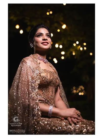 Sindhu looking up into the romantic bokeh of the lights. Her makeup catches the light beautifully, highlighting her features and creating a dreamy, cinematic feel.