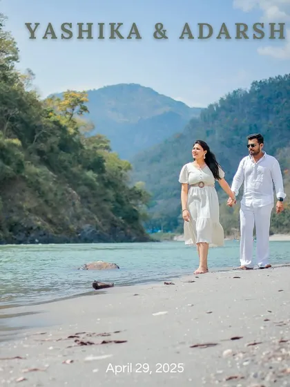 A beautiful save-the-date photo of a couple walking along the sandy banks of the Ganga in Rishikesh, dressed in elegant white.