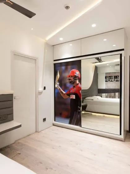A sliding wardrobe with a mirrored panel reflects the room, making the space feel larger. The custom graphic on the mirror adds a personal touch, showcasing our ability to tailor designs to a client's interests, like cricket.