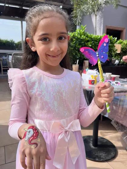 We bring more than just painting! This guest is delighted with her unicorn face paint and a handmade butterfly wand, showing some of the extra fun we can add to your celebration.