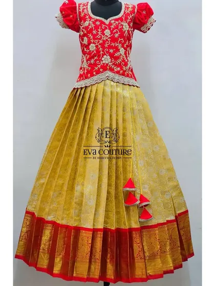 A stunning combination of a yellow Kanchi pattu skirt with a red border and a heavily embroidered red blouse. This is a perfect outfit for festivals like Pongal or Diwali.