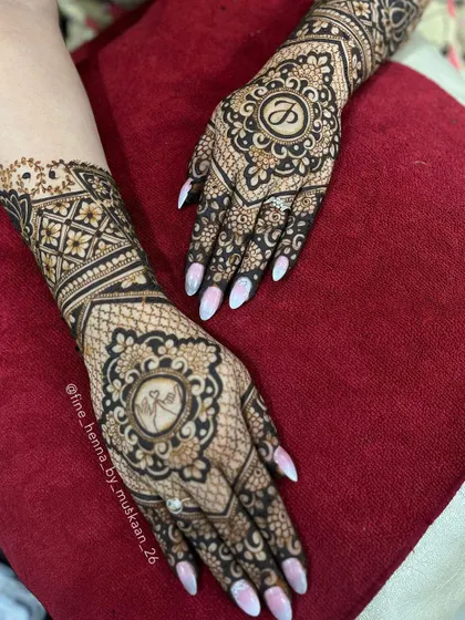 A beautiful roka mehndi design. The back of the hands feature the couple's initials 'P' and 'AK' inside intricate mandalas.