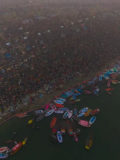 A wider aerial view showing the scale of the crowd along the river during the Kumbh Mela. It gives a sense of the vastness of the event, stretching as far as the eye can see.