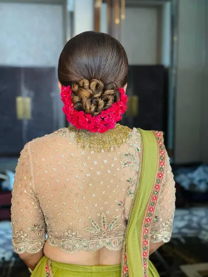 The perfect bridal bun, combining a beautifully crafted rose pattern with a halo of fresh flowers for a truly regal effect.
