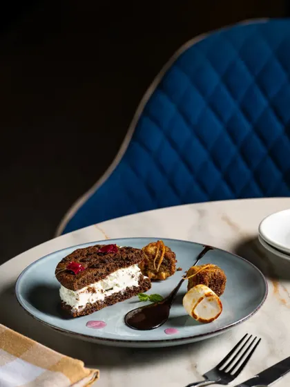 An ice cream sandwich made with chocolate cookies, elegantly plated on a marble table for a fine-dining dessert menu.