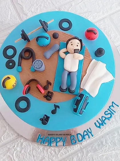 A cake for a fitness enthusiast. The top is decorated with a fondant figurine of Wasim at the gym, surrounded by edible weights, kettlebells, and headphones.