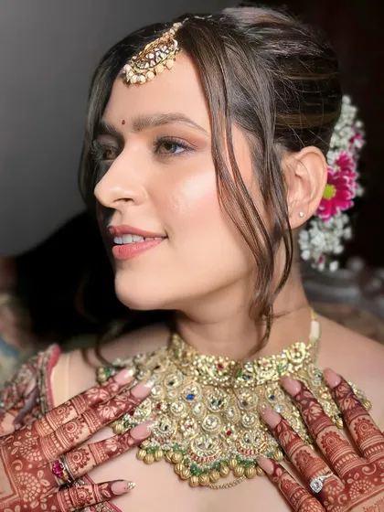 A side profile of this lovely bride shows the soft tendrils framing her face and the floral arrangement in her hair. The makeup highlights her features with a natural, dewy finish.