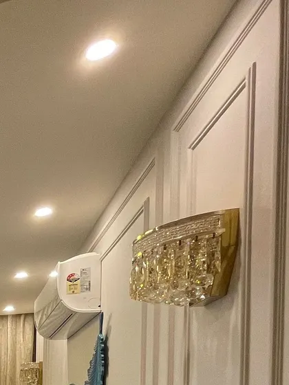 A crystal wall sconce mounted on a paneled wall. The sparkle of the crystal against the classic moulding creates a look of pure luxury.