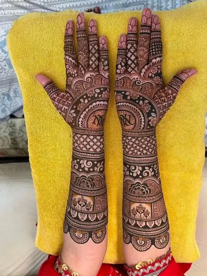 This design incorporates the couple's initials 'N' and 'K' into a central mandala, a popular way to personalize bridal mehndi.
