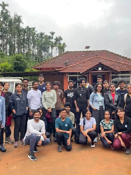 A large group photo outside a tiled-roof homestay, a typical sight in the Western Ghats.