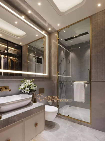 The gold-finished frame of the shower enclosure and the matching fixtures add a touch of glamour to the space.