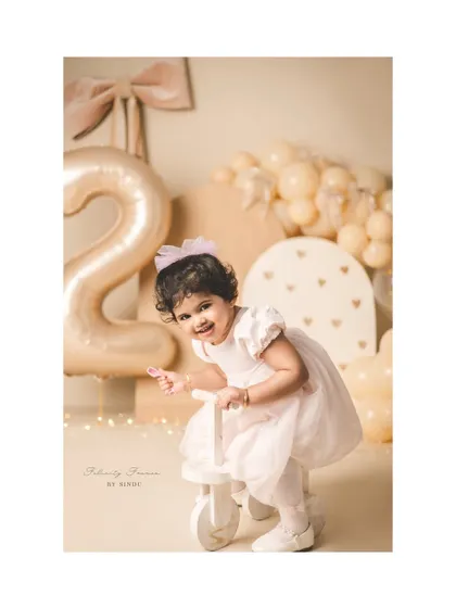 Riding into year two! This little girl is all smiles on her tricycle during her second birthday photoshoot.