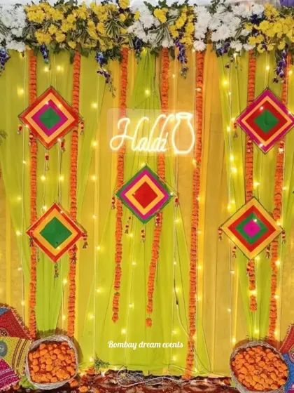 A bright and cheerful Haldi backdrop featuring a neon sign, fairy lights, and colorful Gujarati-style mirror work hangings against a lime-green drape.