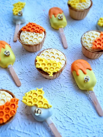 A close-up of the Winnie the Pooh themed cupcakes and cakesicles with a honeycomb design.