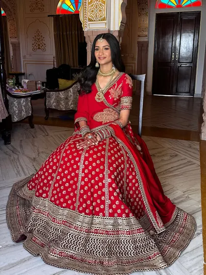 The full view of Aashna's stunning red lehenga. Her simple, elegant makeup and hair ensure that she is the star of the show.