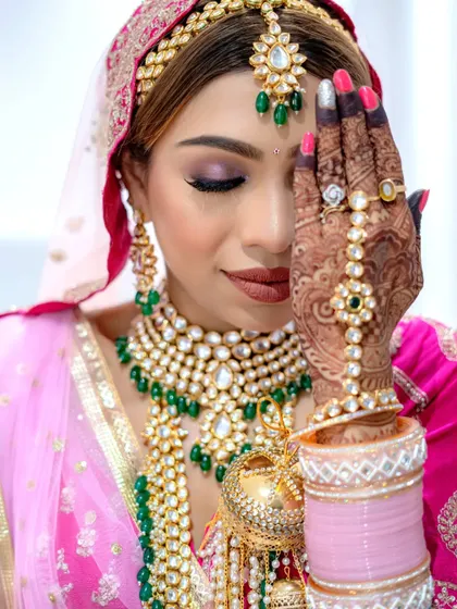A classic bridal pose showing off the intricate henna and the stunning eye makeup.