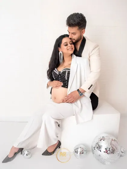 A chic black-and-white themed maternity portrait. The couple's formal wear, combined with the playful disco balls, makes for a modern and sophisticated look.