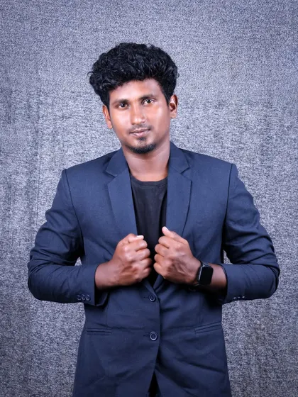A portrait showing a strong and confident stance. The subject is adjusting his blazer, which creates a dynamic and engaging image suitable for a professional profile.