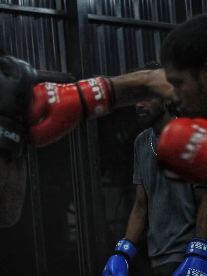 Two fighters trading punches in the dark, gritty atmosphere of our gym. This is where warriors are forged.