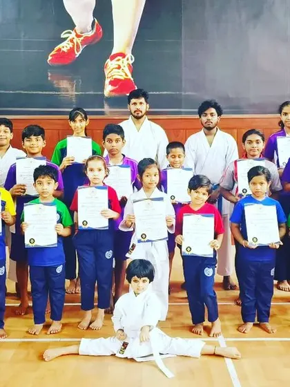A student in the front performs a full split, showing the incredible flexibility and dedication of our young martial artists.