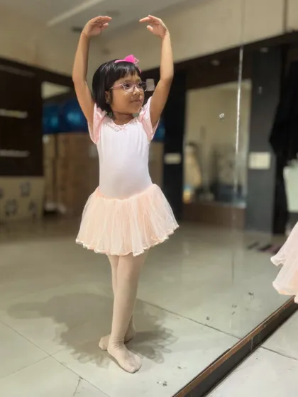 A young student practices her poses in a pink leotard and tutu. Proper attire is encouraged in my ballet classes to help with movement and discipline.