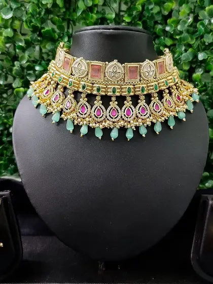 A modern rental choker set with pastel green and pink stones. The matching jhumkas have a unique design, perfect for a contemporary bridal look.