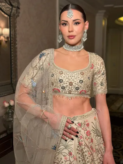 Another angle of this stunning international muse. The makeup is clean and elegant, with a perfectly defined brow and neutral tones that complement the intricate embroidery of her lehenga.