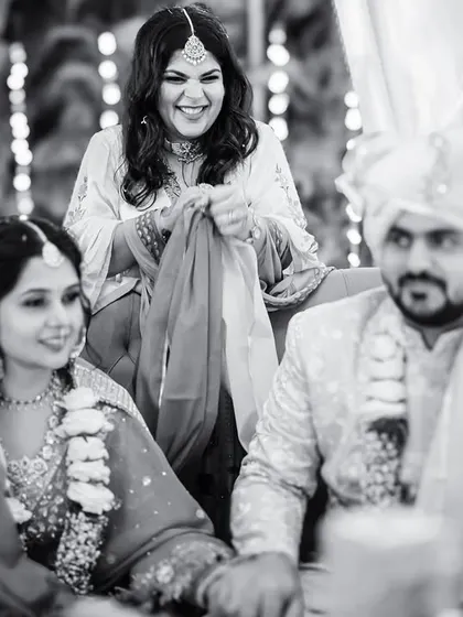 A candid black and white shot of a family member participating in a wedding ritual, her joyful expression adding to the warmth of the ceremony.