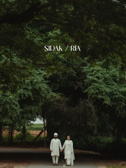 A wide shot of a couple walking hand-in-hand under a large tree, with their names overlaid on the image.