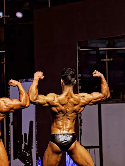 On stage, comparing my back double biceps pose with another competitor. This shows the importance of posing practice to display your physique in the best possible way.