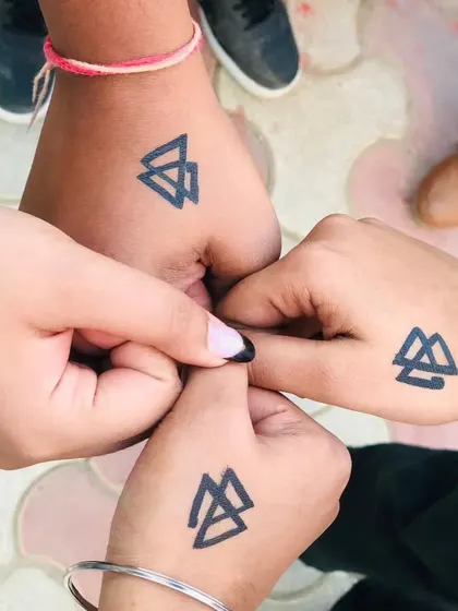 A group of friends with matching geometric Valknut symbols on their hands, celebrating their bond.