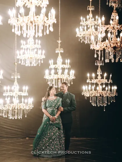 An elegant indoor pre-wedding photo of a couple standing amidst a stunning array of crystal chandeliers, showcasing our ability to create opulent and glamorous studio portraits.