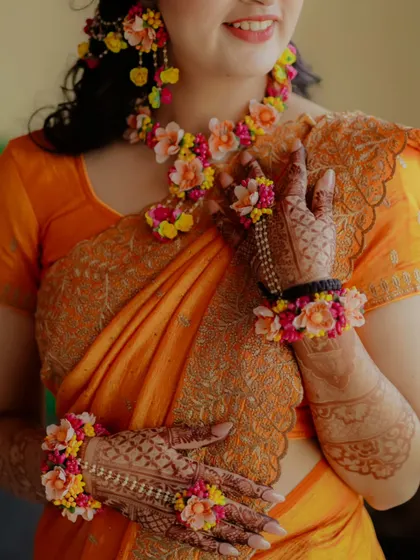 A close up of the bride's hands, showcasing her beautiful mehndi and colorful floral bracelets.