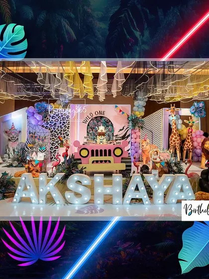 A full view of the impressive neon jungle stage, showcasing the mix of animal props, a central jeep, and a large "AKSHAYA" marquee sign.