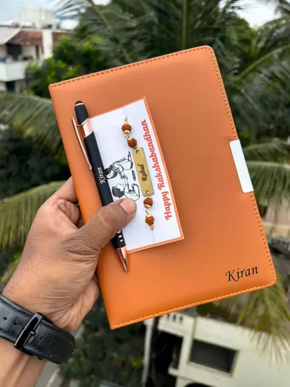 The Orion diary, Krysta pen, and Rudraksh rakhi set, shown here in a classic tan color. All three items can be personalized for a coordinated and thoughtful Rakhi gift.
