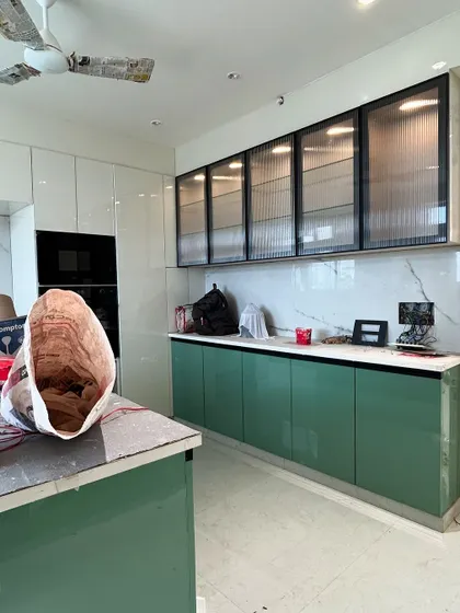 This image shows the kitchen nearing completion, with the built-in oven unit and handle-less cabinets. The combination of green, white, and fluted glass creates a fresh and modern vibe.